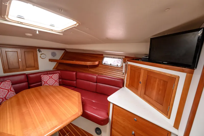 Slide: The Image of 2005 MJM 34z Downeast yacht interior with red seating, wooden table, and TV. - 20