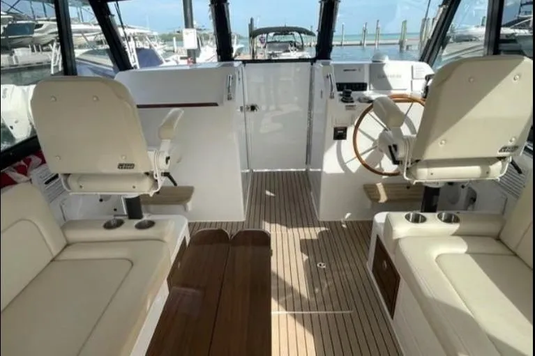 Slide: The Image of 2022 MJM 3 boat interior with helm, seating, and wooden flooring at a marina. - 3