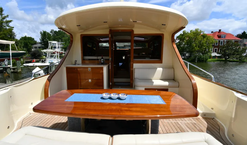 Slide: The Image of 2020 Palm Beach Motor Yachts PB52, elegant deck with wooden table and seating, docked by the water. - 11
