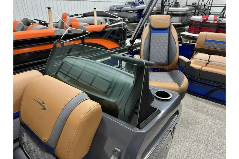 Slide: The Image of 2026 Bennington 22 SSB Swingback interior with tan and gray seating, cup holder, and windshield. - 15