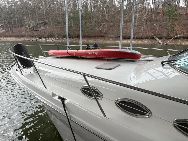 Slide: The Image of 1995 Sea Ray Sundancer 370 with paddleboard on deck, docked by lakeside. - 4