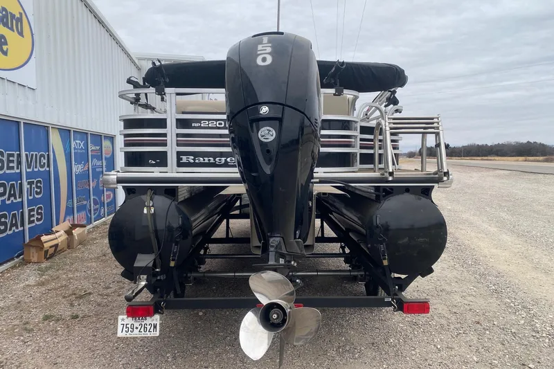 Slide: The Image of 2024 Ranger Reata 220F pontoon boat with powerful outboard motor, parked near dealership. - 5