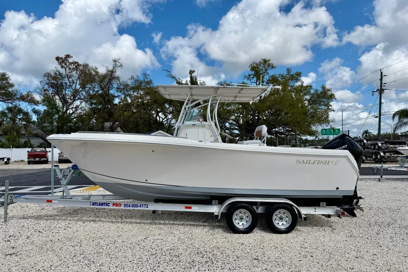 The Image of 2021 Sailfish 242 CC boat on trailer, parked outdoors under a partly cloudy sky. - 0
