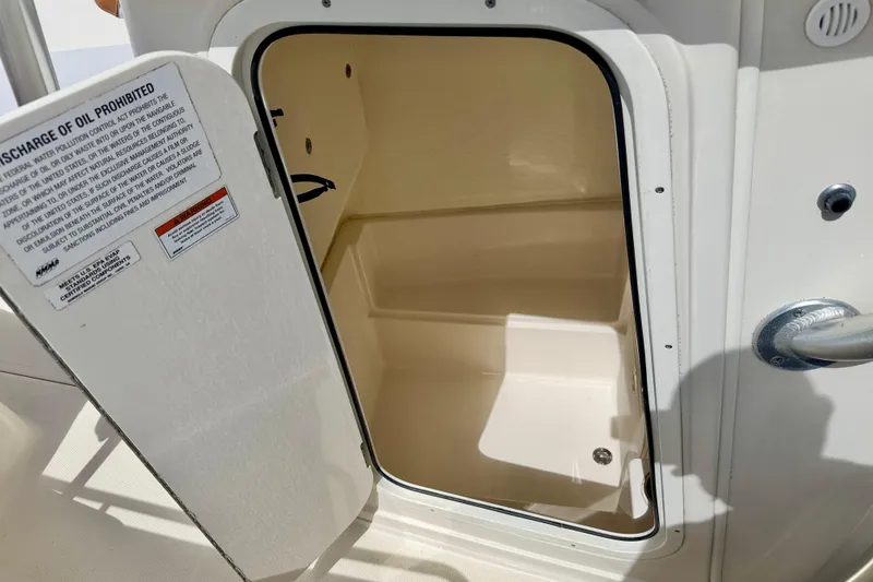 Slide: The Image of Open storage compartment on 2021 Sailfish 242 CC boat, featuring a warning label. - 26