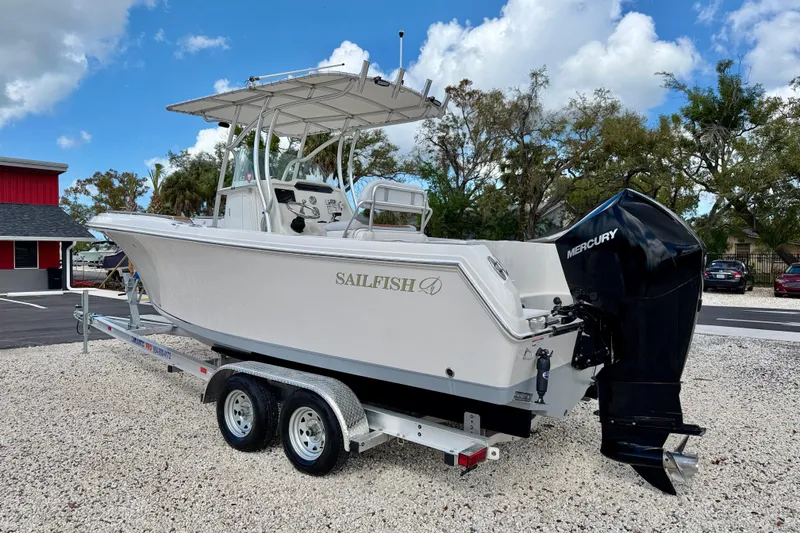 Slide: The Image of 2021 Sailfish 242 CC boat on trailer with Mercury outboard motor, parked outdoors. - 7
