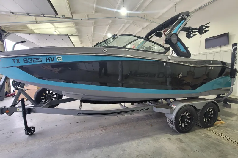 Slide: The Image of 2022 MasterCraft X22 boat on trailer in a garage setting. - 11