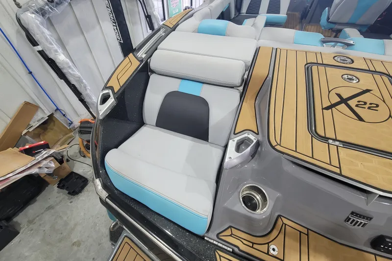 Slide: The Image of 2022 MasterCraft X22 boat interior with cushioned seating and teak-style flooring. - 16