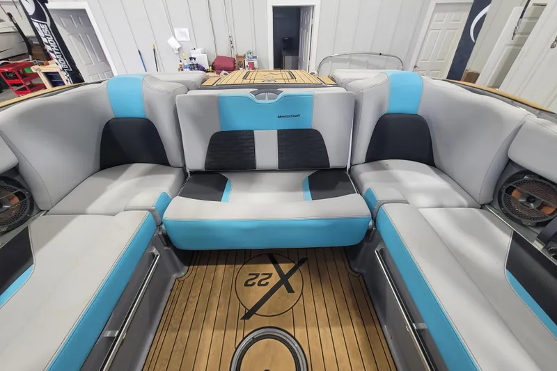 Slide: The Image of 2022 MasterCraft X22 boat interior with blue and gray seating, wooden flooring. - 19