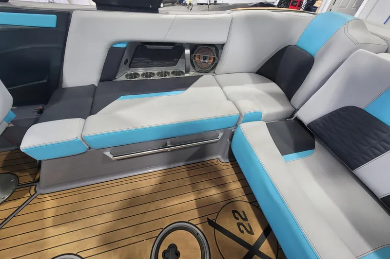 Slide: The Image of 2022 MasterCraft X22 interior with blue and gray seating, wooden flooring, and speaker system. - 22