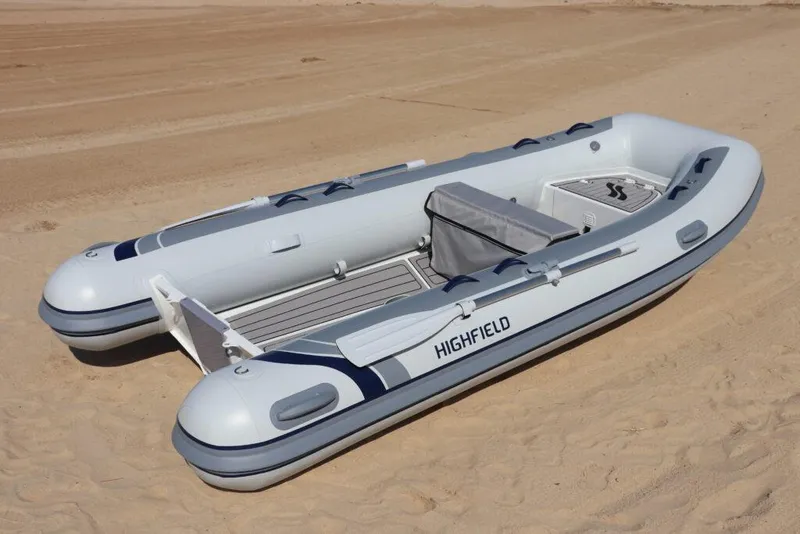 Slide: The Image of 2026 Highfield Classic 360 inflatable boat on sandy beach. - 2
