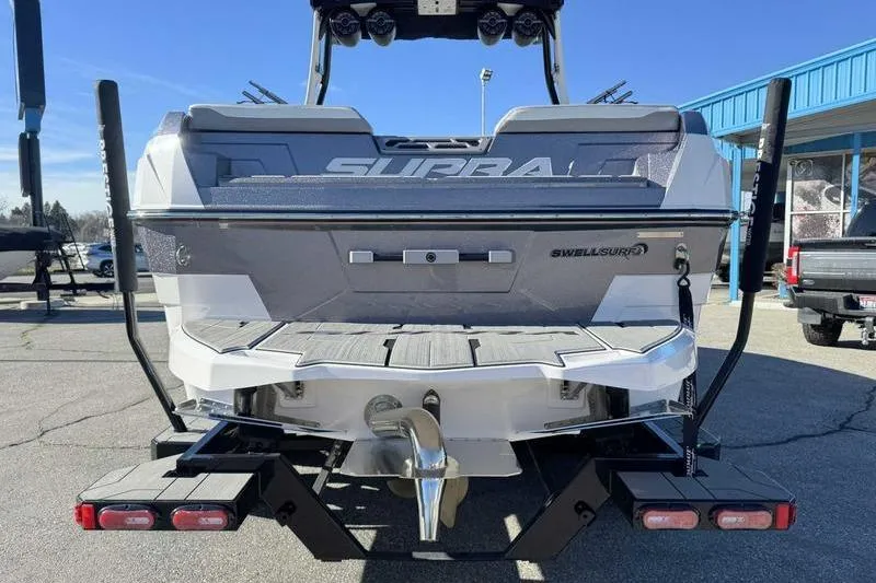 Slide: The Image of 2022 Supra SL boat rear view with SwellSurf system, parked outdoors. - 10