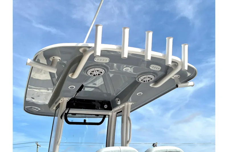 Slide: The Image of 2026 Sportsman Heritage 231 Center Console T-top with rod holders and speakers against blue sky. - 13