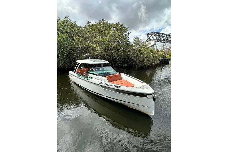 The Image of 2023 Saxdor 320 GTO boat on calm water, surrounded by lush greenery. - 0