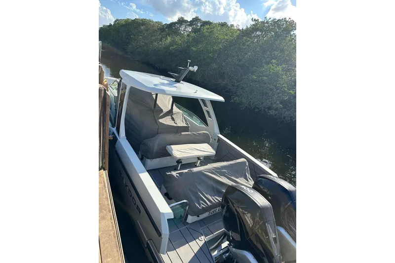 Slide: The Image of 2023 Saxdor 320 GTO boat docked by a lush riverside under a clear sky. - 10