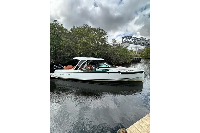 Slide: The Image of 2023 Saxdor 320 GTO boat docked on a calm river under cloudy skies. - 11