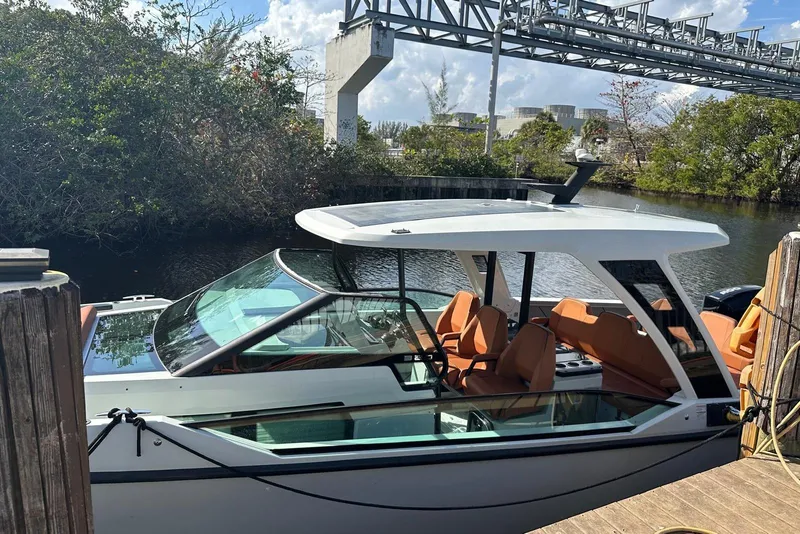 Slide: The Image of 2023 Saxdor 320 GTO boat docked by a scenic waterway with lush greenery. - 12