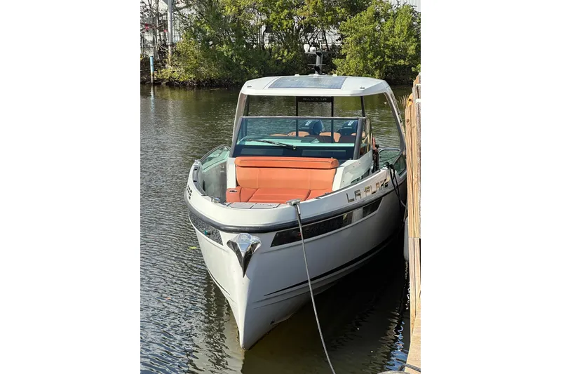 Slide: The Image of 2023 Saxdor 320 GTO boat docked on calm water, featuring sleek design and orange seating. - 13