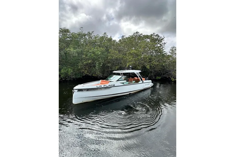 Slide: The Image of 2023 Saxdor 320 GTO boat on calm water, surrounded by lush greenery. - 15