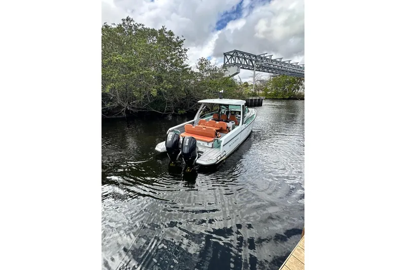 Slide: The Image of 2023 Saxdor 320 GTO boat on water near trees and bridge, featuring dual engines. - 16
