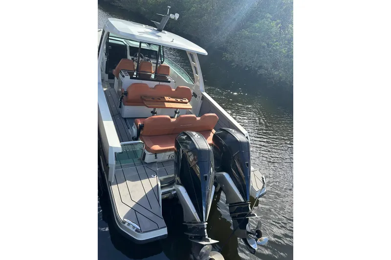 Slide: The Image of 2023 Saxdor 320 GTO boat with dual engines and orange seating on a calm waterway. - 2