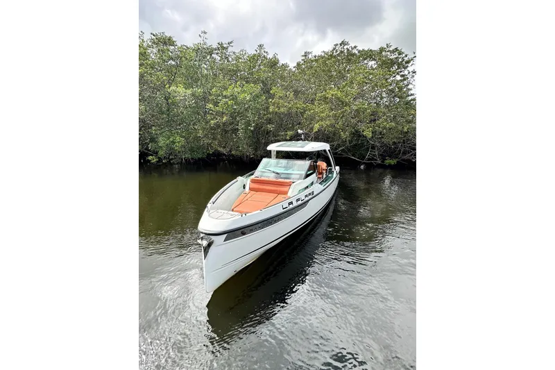 Slide: The Image of 2023 Saxdor 320 GTO boat on calm water, surrounded by lush greenery. - 4