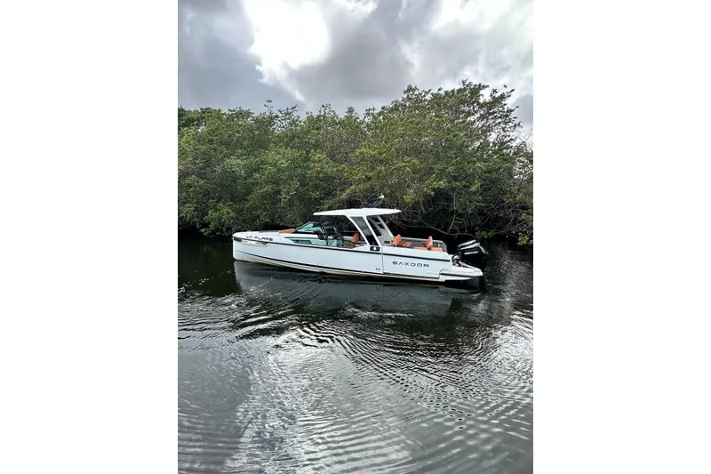 Slide: The Image of 2023 Saxdor 320 GTO boat on calm water near lush greenery. - 6
