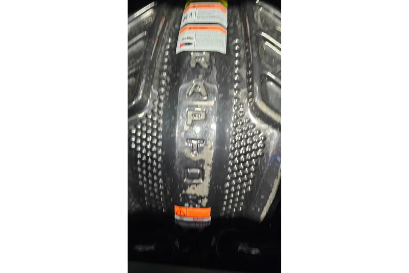 Slide: The Image of 2023 Supra SE 550 engine cover with textured design and warning labels. - 23