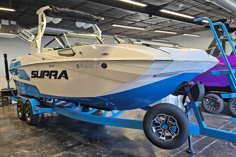 Slide: The Image of 2023 Supra SE 550 boat on trailer in showroom, featuring sleek design and blue accents. - 4