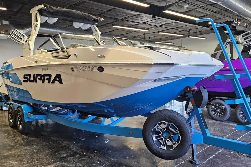 Slide: The Image of 2023 Supra SE 550 boat on trailer in showroom, featuring sleek design and blue accents. - 5