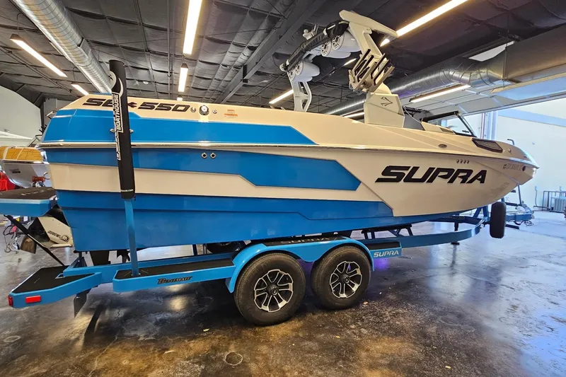 Slide: The Image of 2023 Supra SE 550 boat in a showroom, featuring a sleek blue and white design. - 6