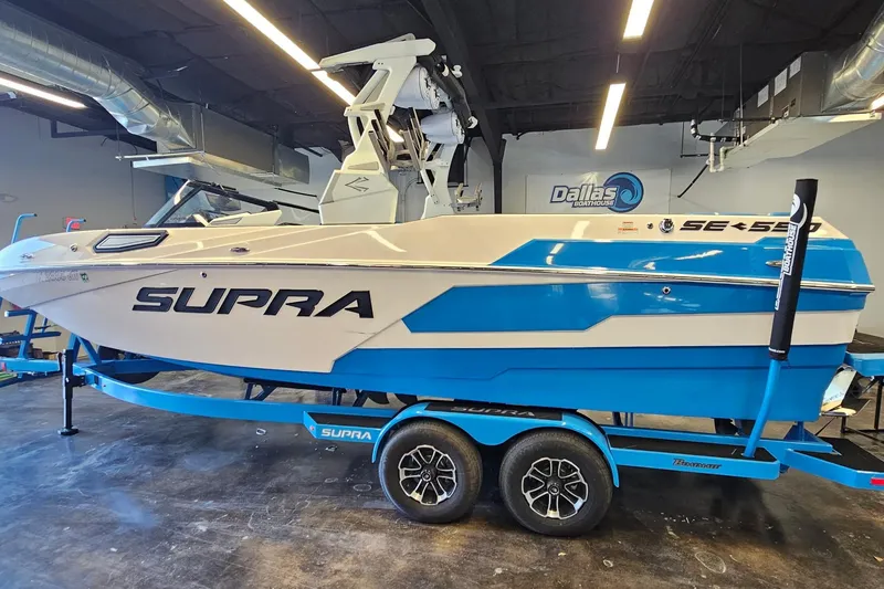 Slide: The Image of 2023 Supra SE 550 boat in showroom, blue and white design, on trailer. - 9