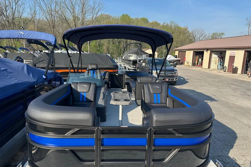 Slide: The Image of 2026 Bennington 22 SSR Quad Bench pontoon boat with blue accents, parked outdoors. - 6