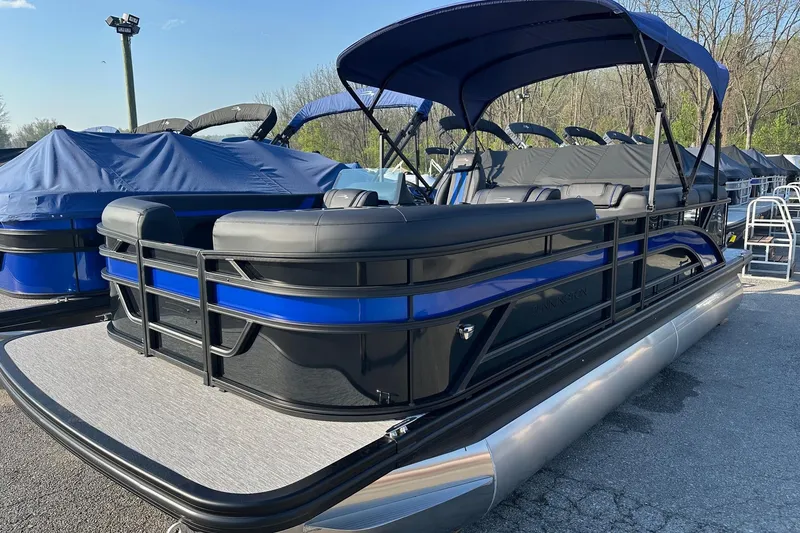 Slide: The Image of 2026 Bennington 22 SSR Quad Bench pontoon boat with blue and black design, docked outdoors. - 7