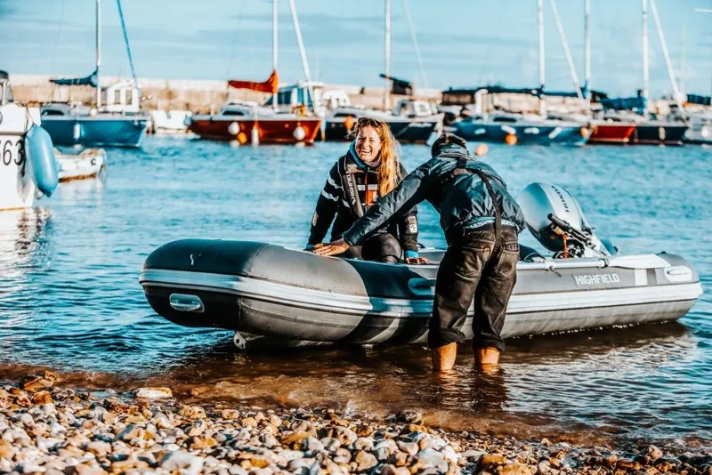 Slide: The Image of Two people on a Highfield Classic 360 boat at the beach. - 1
