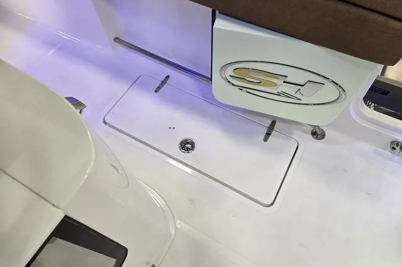 Slide: The Image of 2026 Sea Hunt Gamefish 27 Forward Seating boat interior with storage compartment and logo. - 16