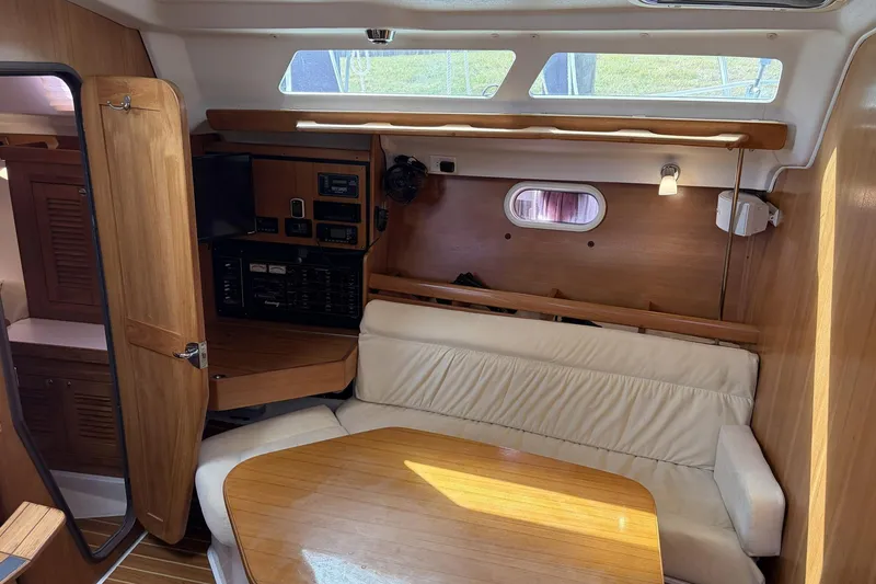 Slide: The Image of 2004 Catalina 36 MkII yacht interior with wood finish, beige seating, and navigation equipment. - 24