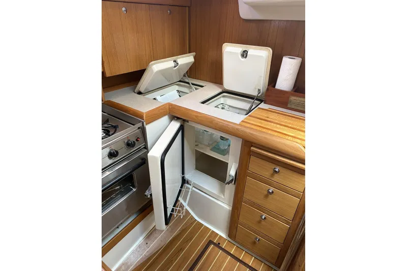 Slide: The Image of 2004 Catalina 36 MkII yacht kitchen with stove, fridge, and wooden cabinetry. - 28