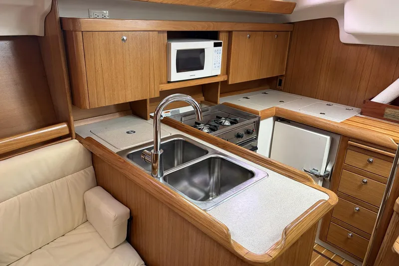 Slide: The Image of 2004 Catalina 36 MkII yacht kitchen with wood cabinetry, double sink, stove, and microwave. - 30