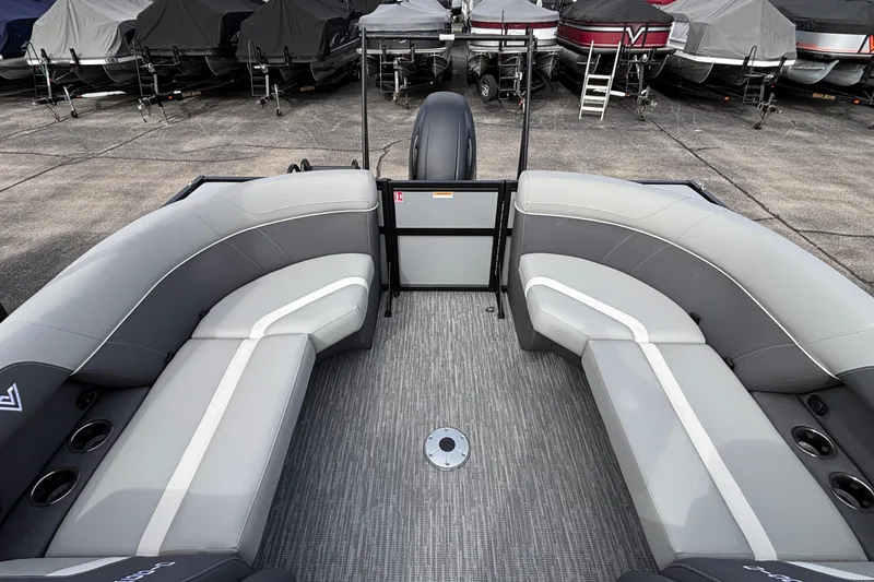 Slide: The Image of 2026 Viaggio X24U boat interior with gray seating and cup holders, docked among covered boats. - 15