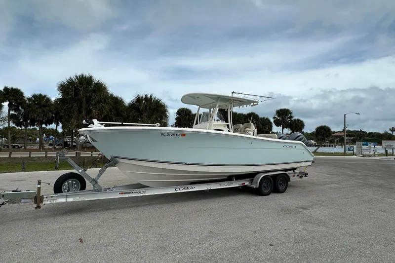 Slide: The Image of 2016 Cobia 277 Center Console boat on trailer, parked near palm trees. - 2