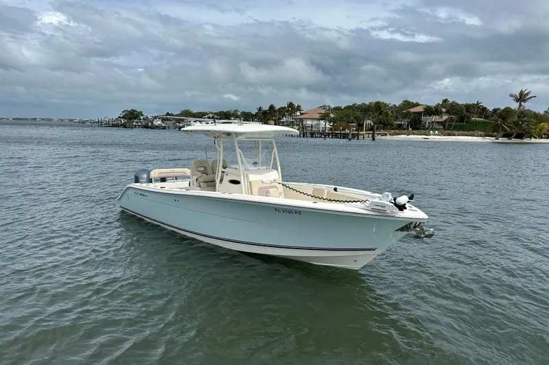 Slide: The Image of 2016 Cobia 277 Center Console boat on calm water near a coastal shoreline. - 4