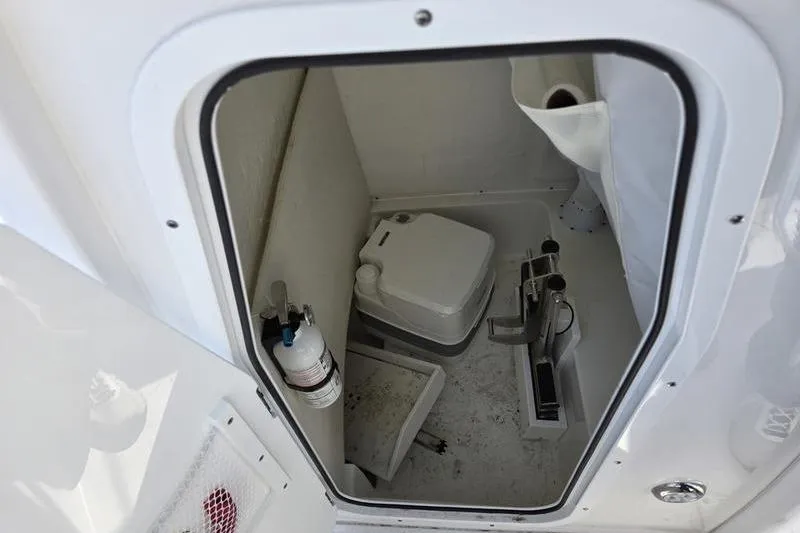 Slide: The Image of 2023 Sea Hunt Ultra 239 SE boat interior with compact marine toilet and storage. - 16