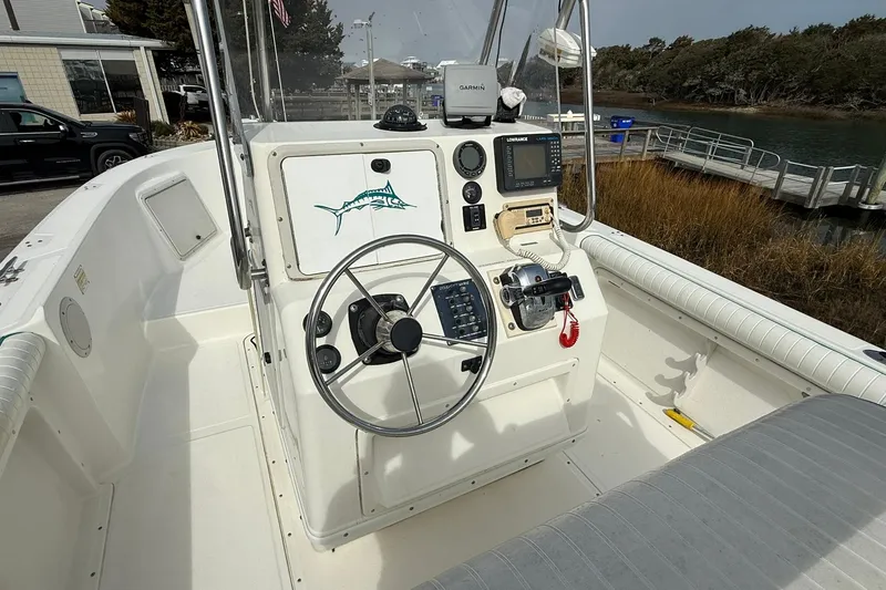 Slide: The Image of 1995 Marlin 210 boat cockpit with steering wheel, navigation equipment, and waterfront view. - 10