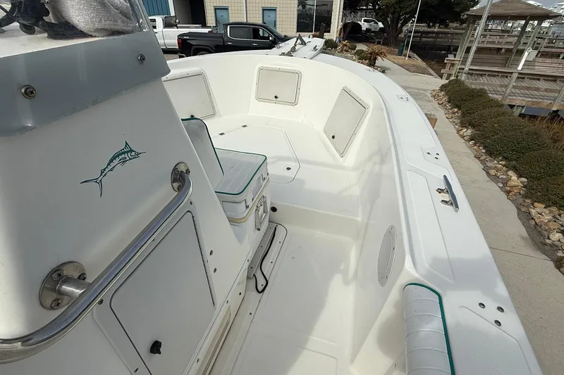 Slide: The Image of 1995 Marlin 210 boat interior with seating and storage, docked near a marina. - 13