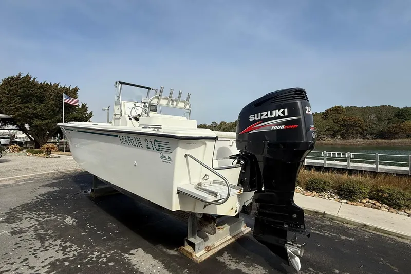 Slide: The Image of 1995 Marlin 210 boat with Suzuki outboard motor, docked near a scenic waterfront. - 5