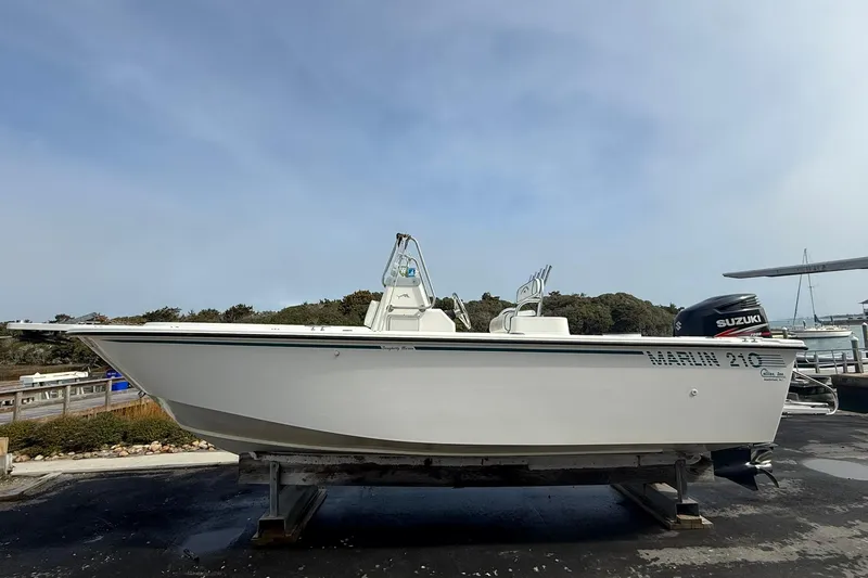 Slide: The Image of 1995 Marlin 210 boat with Suzuki engine on display at a marina. - 6