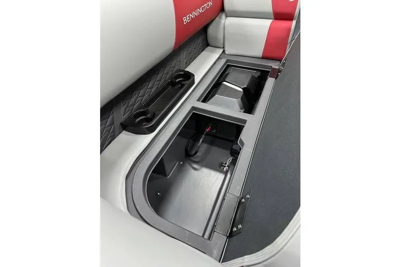Slide: The Image of 2026 Bennington 22 SSR Quad Bench interior storage compartment with cup holders and red accents. - 10