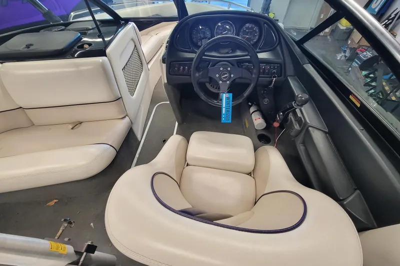 Slide: The Image of 2003 Malibu Sunsetter LXi boat interior with steering wheel and beige seating. - 11