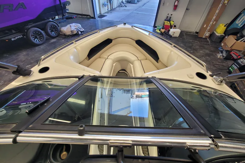 Slide: The Image of 2003 Malibu Sunsetter LXi boat interior with beige seating, in a garage setting. - 12