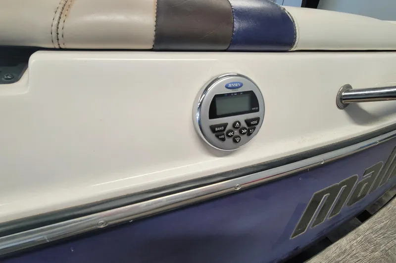 Slide: The Image of 2003 Malibu Sunsetter LXi boat interior with Jensen stereo system and cushioned seating. - 20